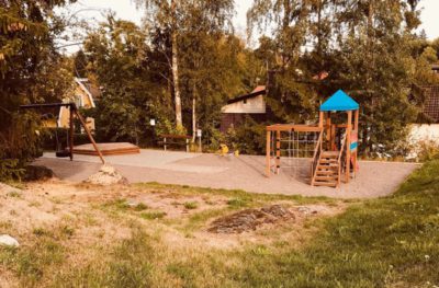 Bild på lekpark omringad av sko, hus och gräs.