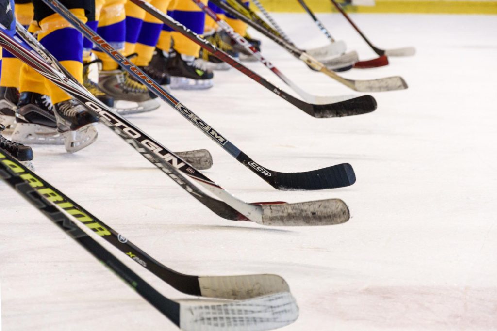 Ishockeyspelare står uppradade på isen med sina klubbor.